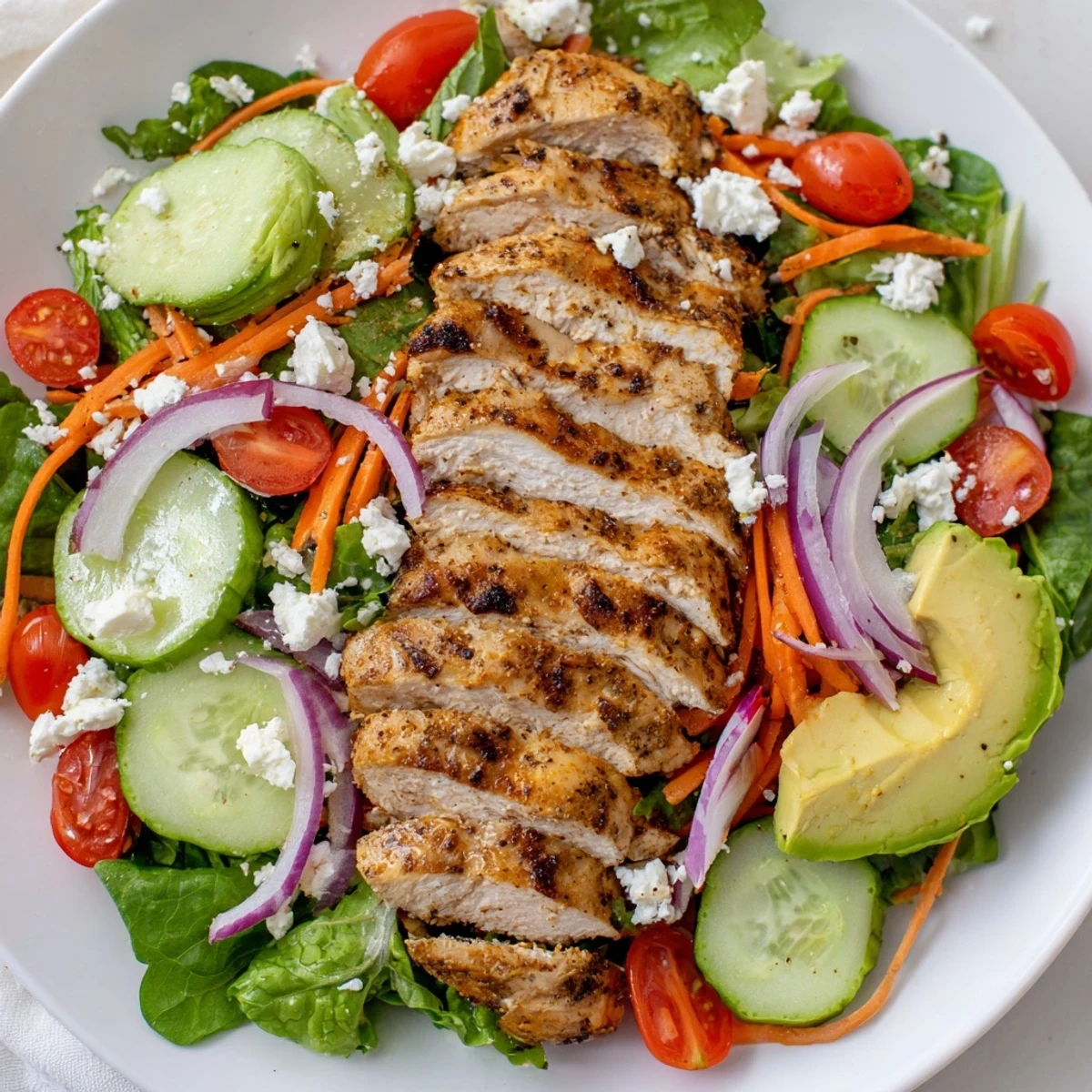 Sliced grilled Chicken Meal Prep Salad with tomatoes, cucumbers, and tangy lemon dressing.  