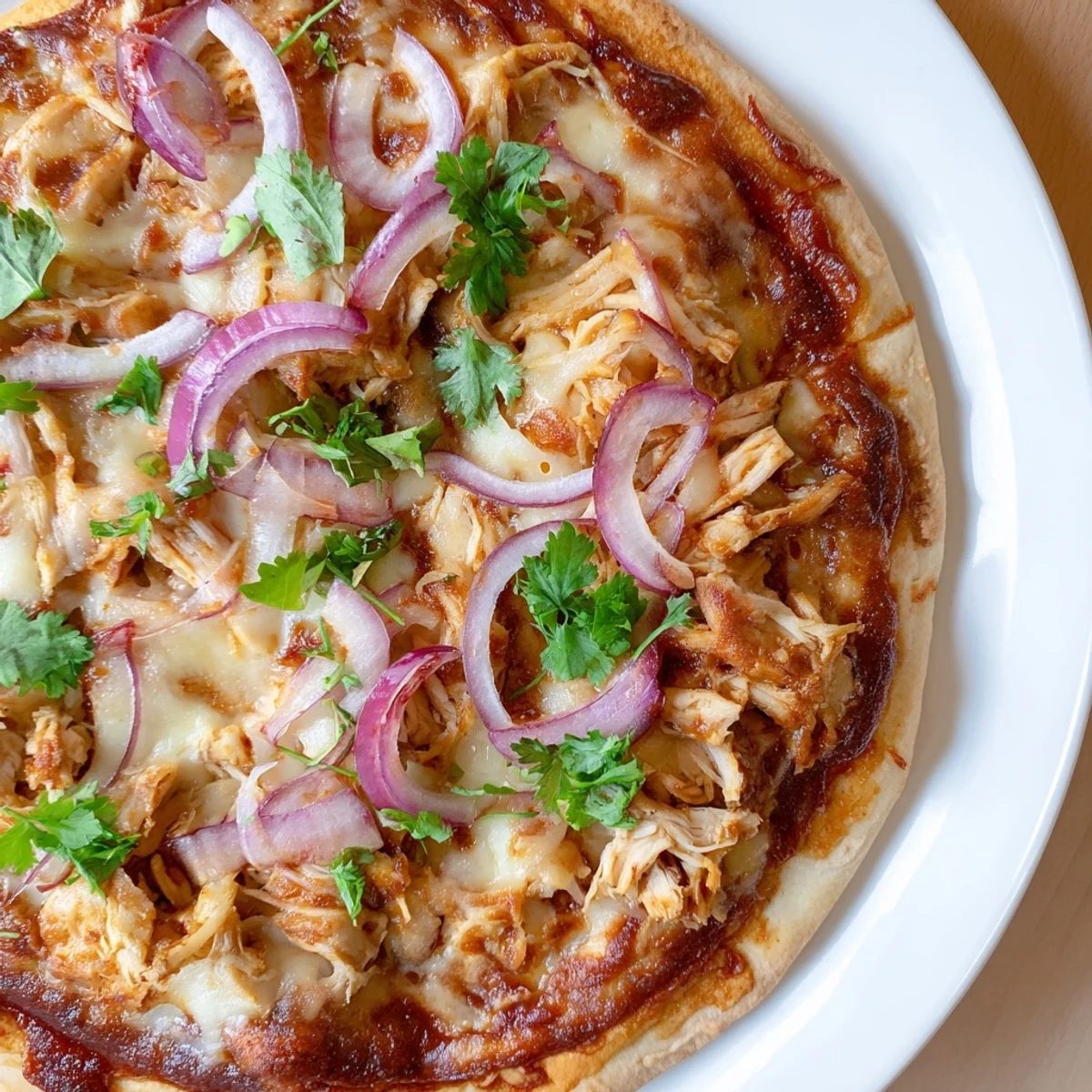 Sliced BBQ Chicken Pizza with red onion and cilantro on a wooden board, ready to serve.