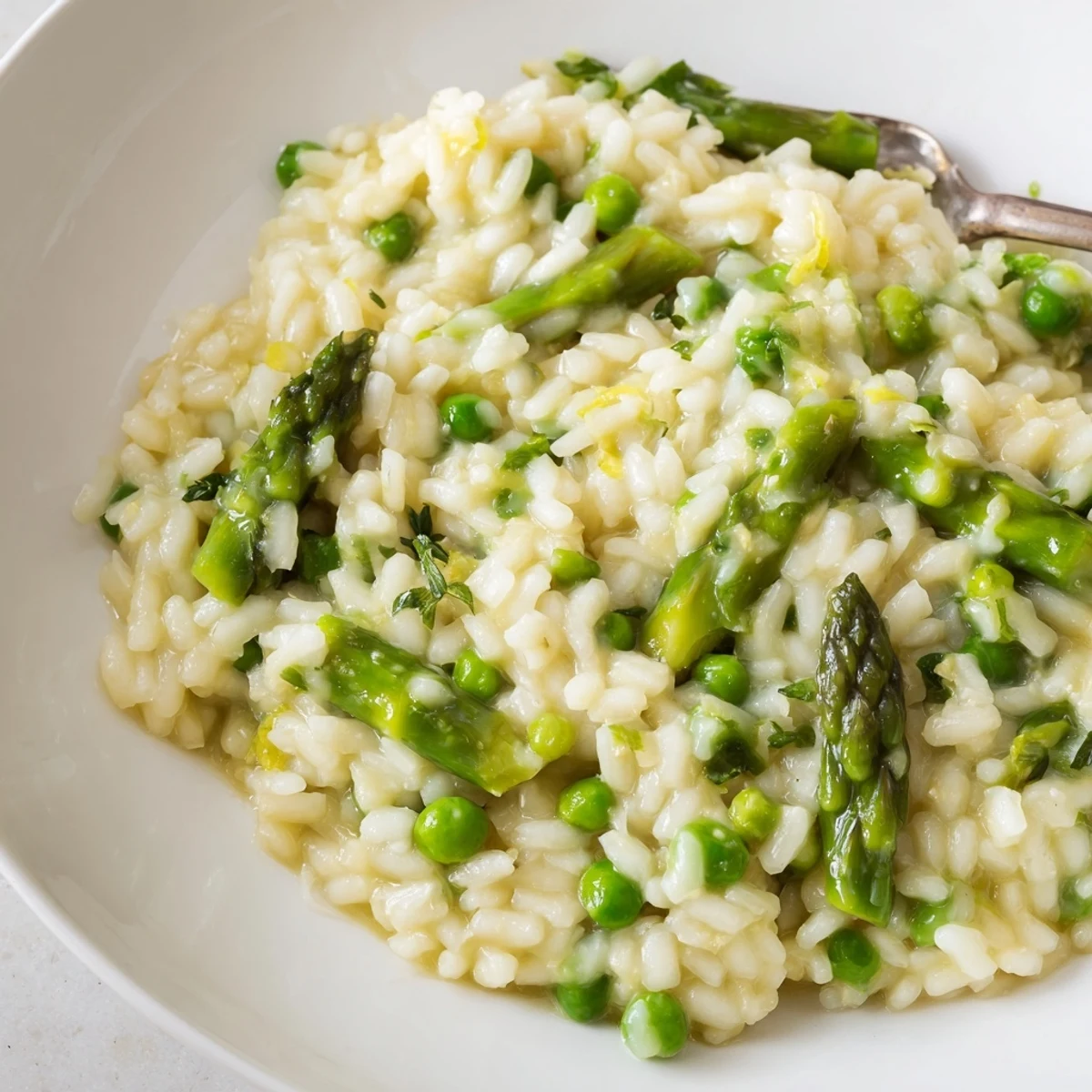 Velvety Arborio rice blends with tender asparagus and sweet peas in this creamy Parmesan risotto, served warm in a bowl.