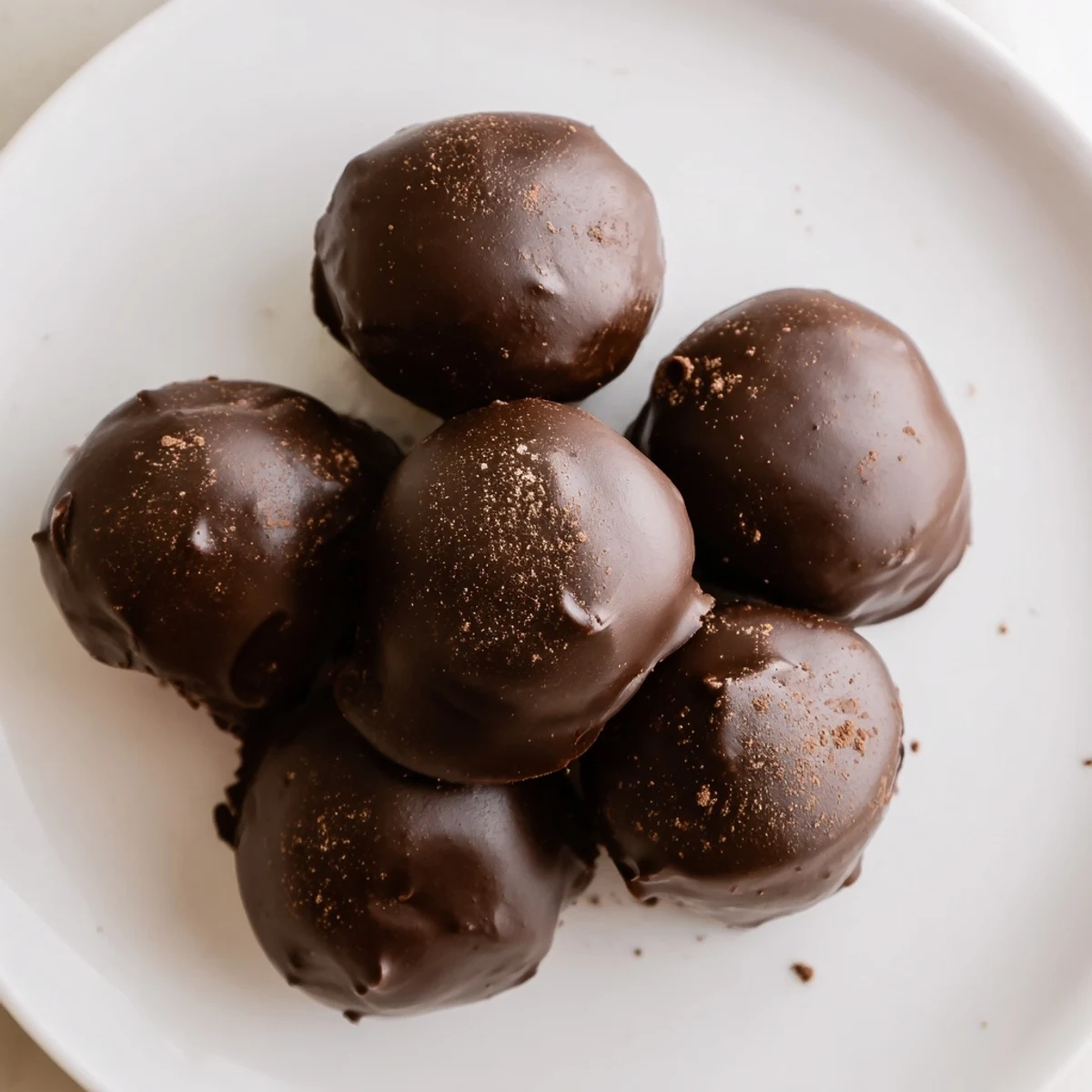 A stack of Irish Cream Truffles with Dark Chocolate wrapped in gold foil, ready for gifting on a rustic wooden table.