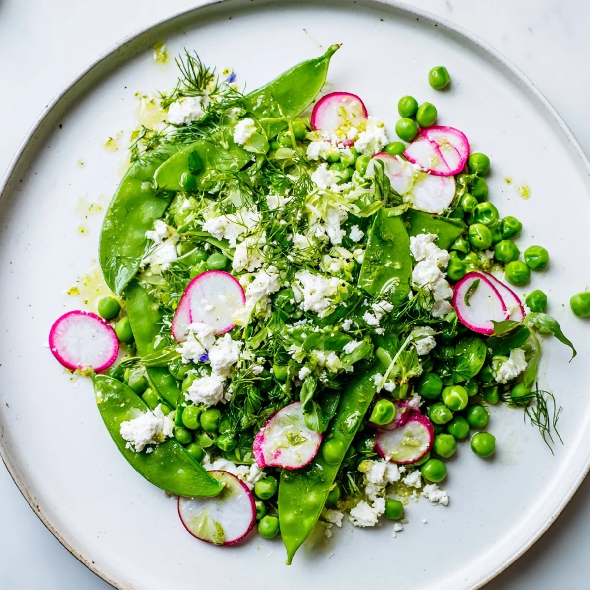 Crisp Spring Pea Salad with Radishes and Feta tossed in a lemon-herb dressing, ready to serve as a side.