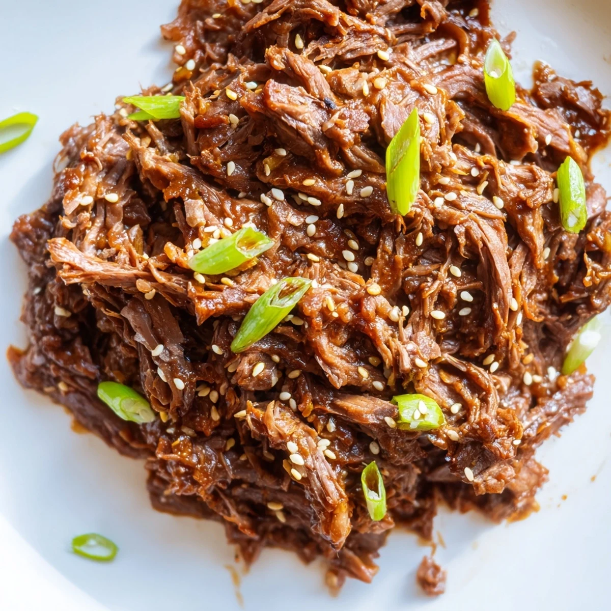 Savory shredded Crock Pot Korean Beef simmered in a sticky sweet glaze, served over fluffy jasmine rice with green onions.
