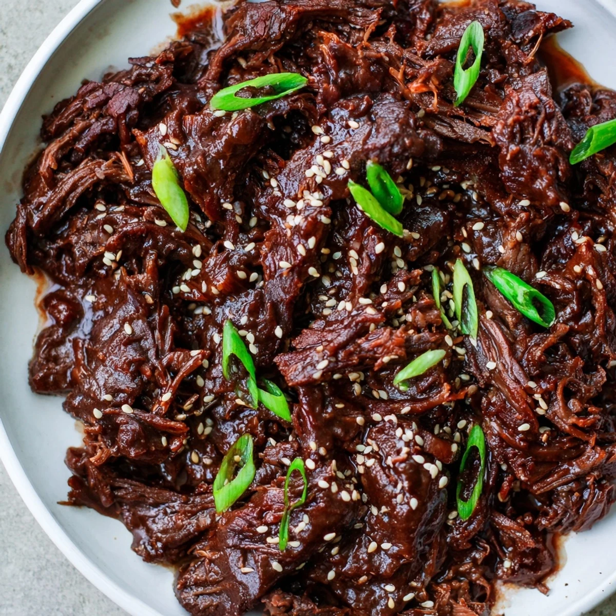 Easy Crock Pot Korean Beef piled high on white rice, featuring juicy shredded beef and a rich, garlicky Korean-style sauce.