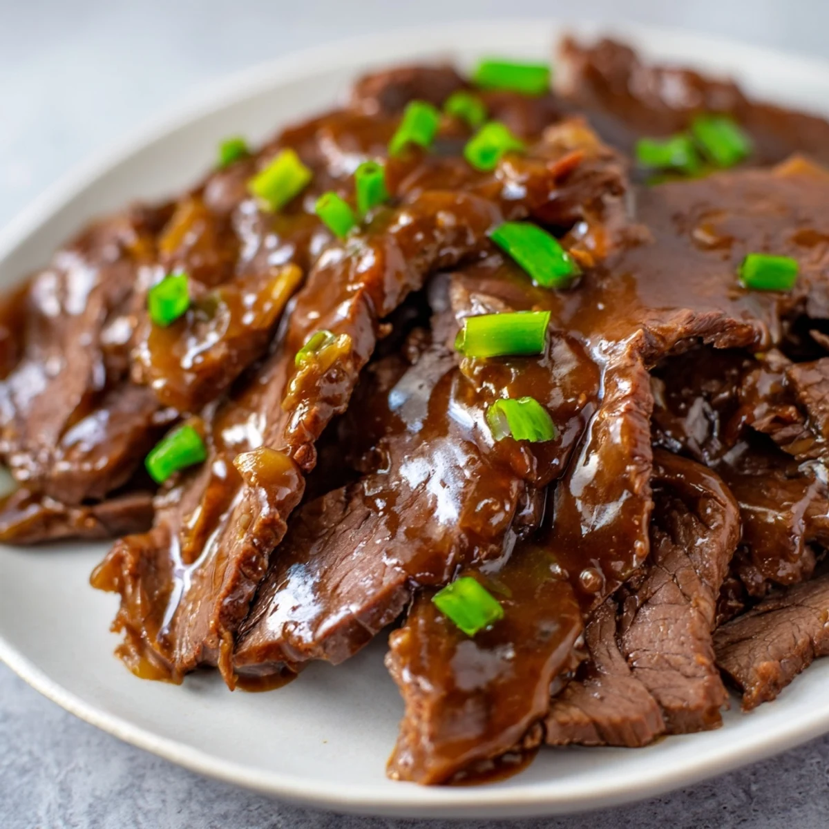 Savory Ultimate Slow Cooker Mongolian Beef served over steamed rice with green onions and sesame garnish.