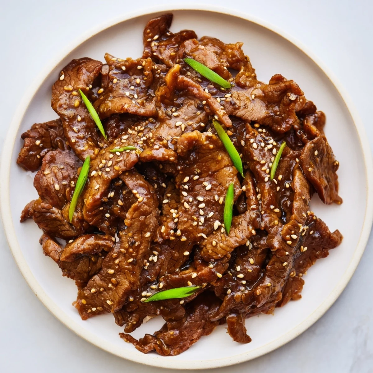 Tender beef slices glistening in glossy sauce over rice for Ultimate Slow Cooker Mongolian Beef