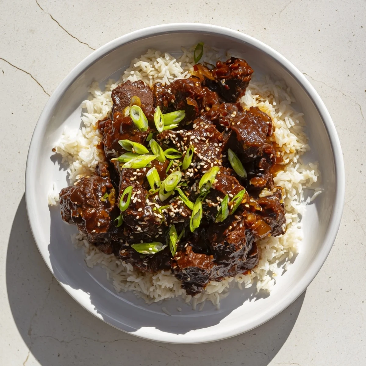 Tender shredded Crock Pot Korean Beef piled high with onions and sesame seeds, served over steamed jasmine rice.