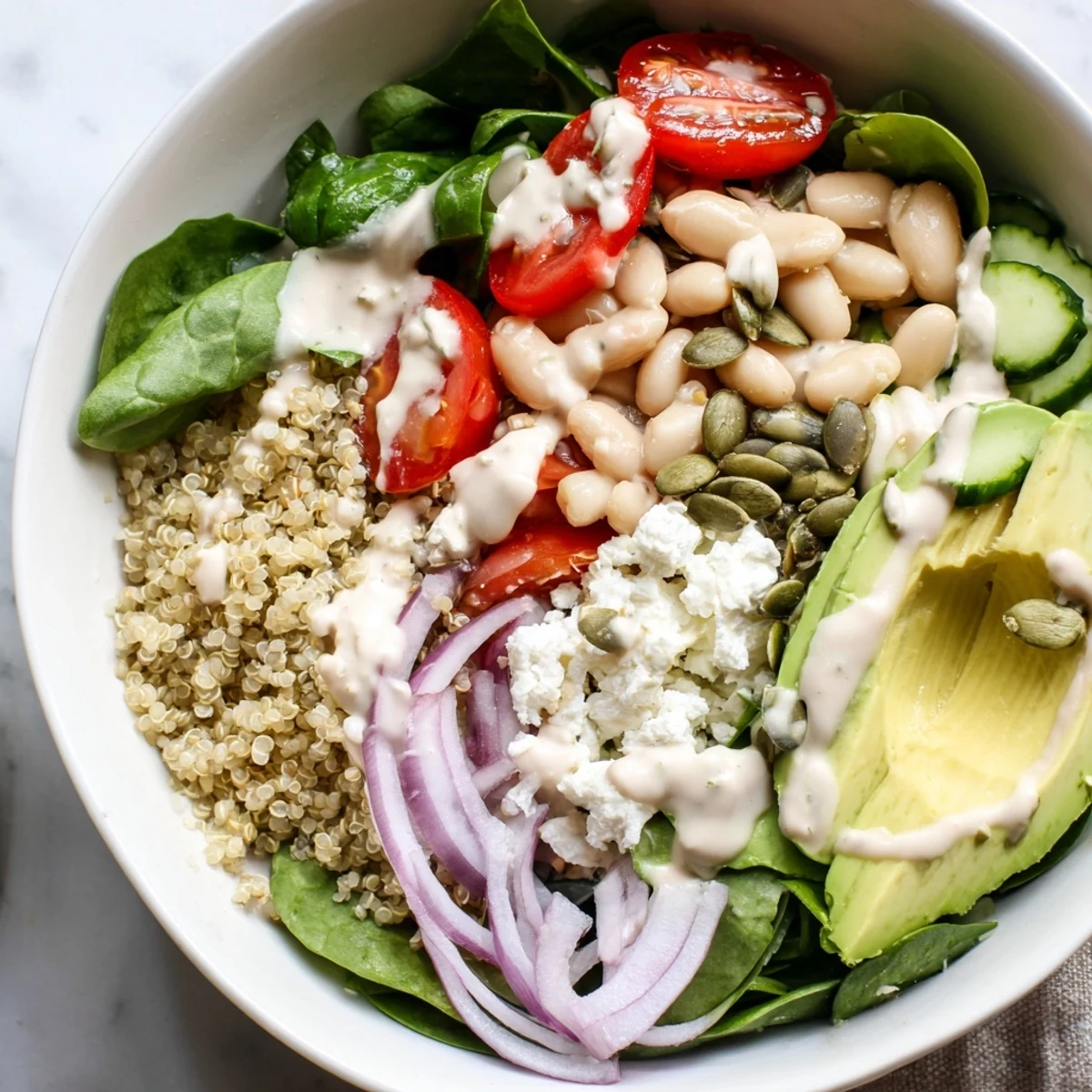 Served in a ceramic bowl, the Spinach & White Bean Ultimate Protein Power Bowl features pumpkin seeds and cherry tomatoes.
