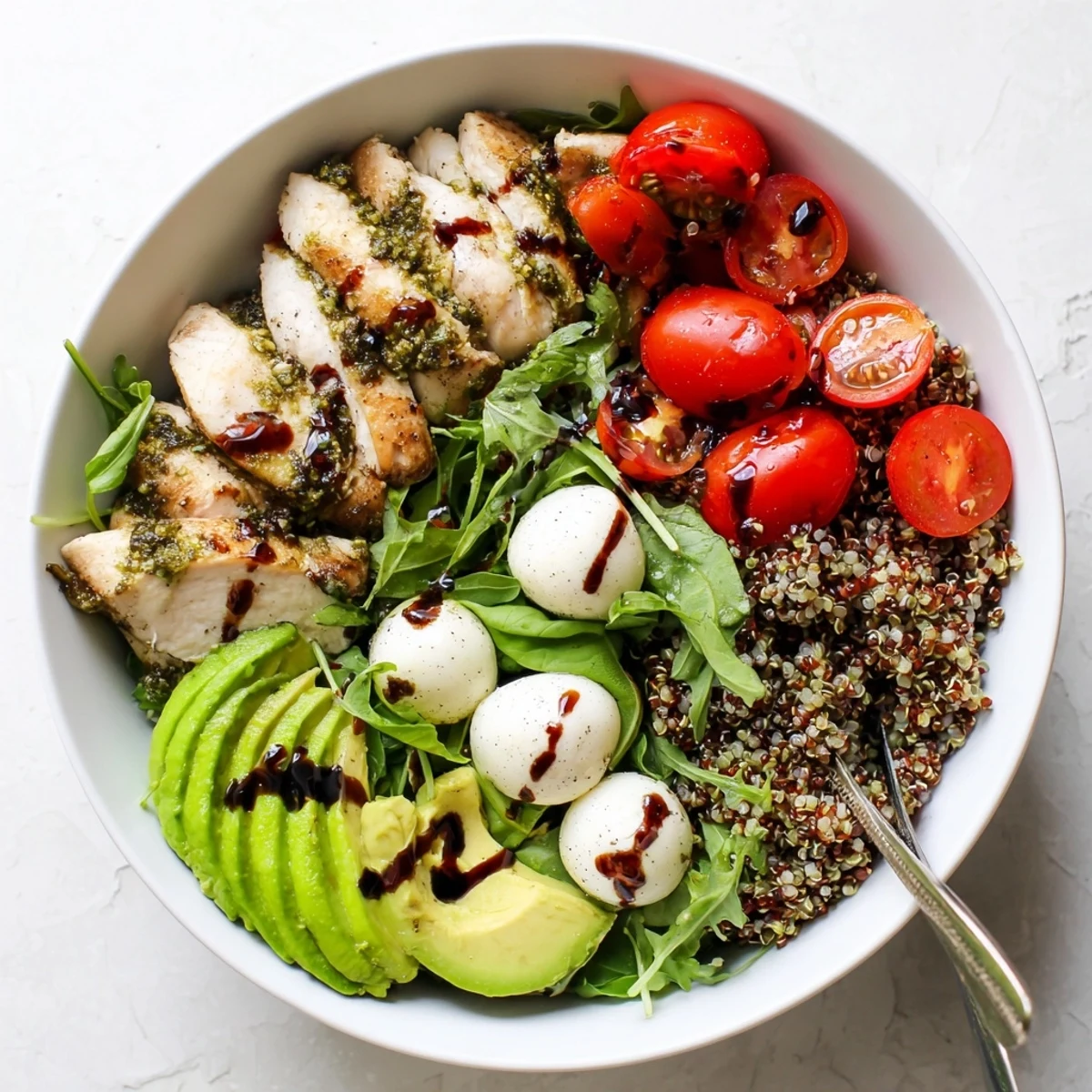 Juicy pesto-marinated chicken, fresh mozzarella, and tomatoes in a vibrant Pesto Chicken Caprese Grain Bowl served over greens.