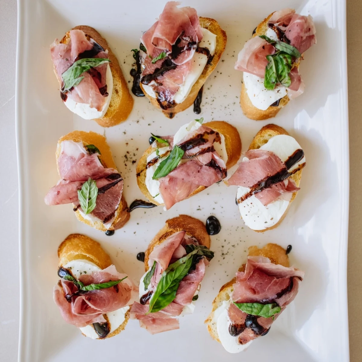 A close-up of Mozzarella Beef Prosciutto Crostini on a rustic wooden board, featuring crisp bread, delicate prosciutto, and a drizzle of balsamic glaze ready for a party platter.