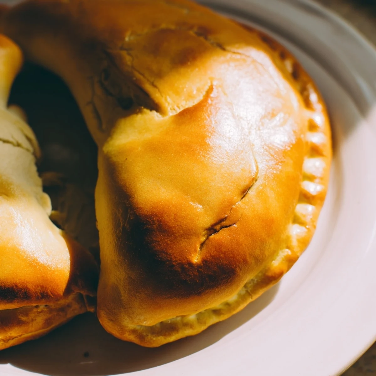 Close-up of a split Cheesy Egg and Cheese Piroshki revealing a rich, creamy filling of chopped eggs, mozzarella, feta, and fresh dill.