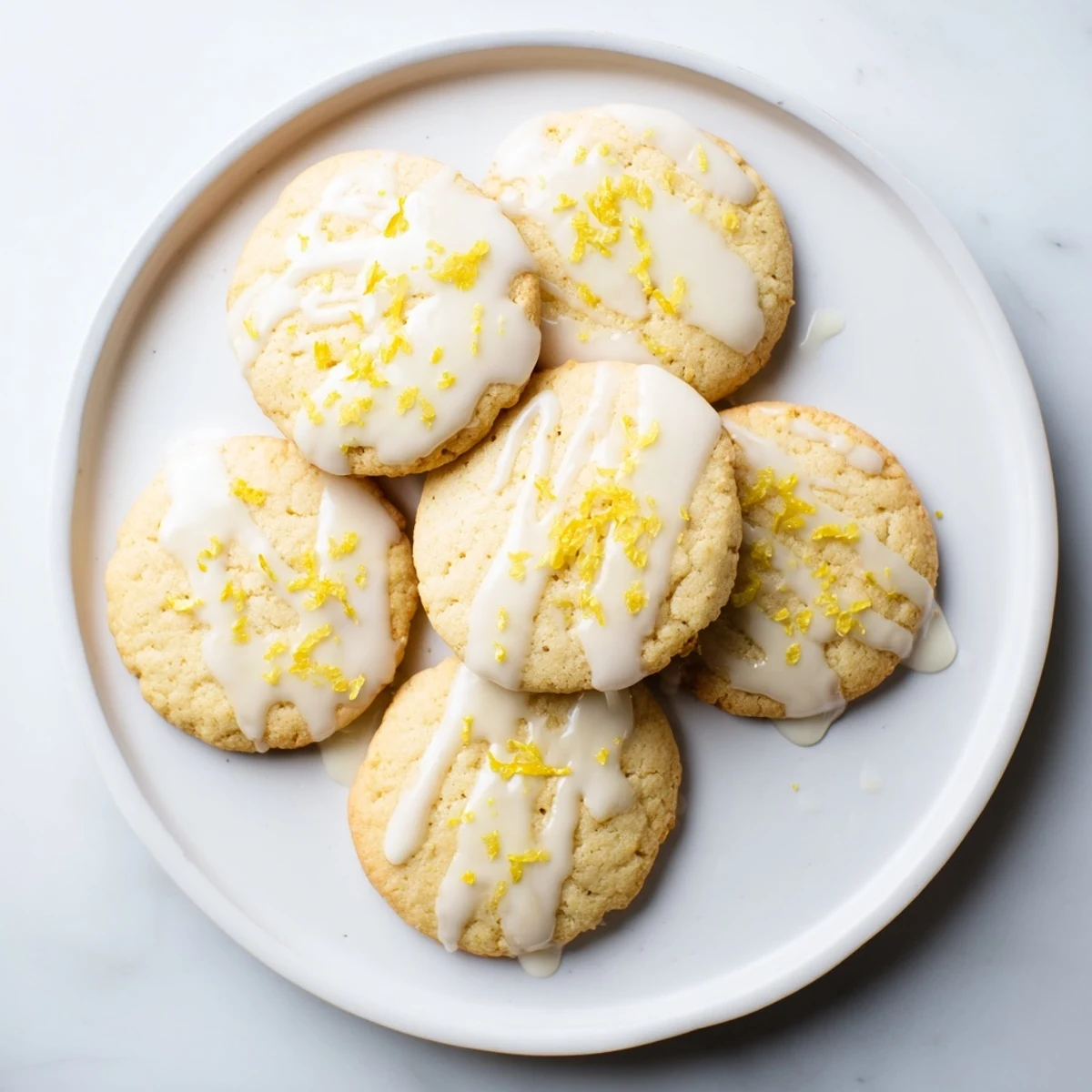 Stack of Limoncello Cookies showcasing their soft texture and zesty glaze, with scattered lemon slices and a bottle of Limoncello nearby.