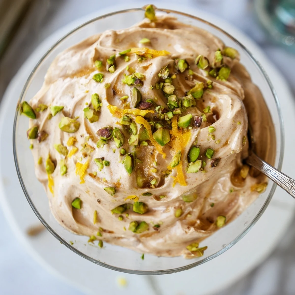Light Lebanese date orange blossom mousse serving glasses decorated with nutty pistachios and grated orange peel