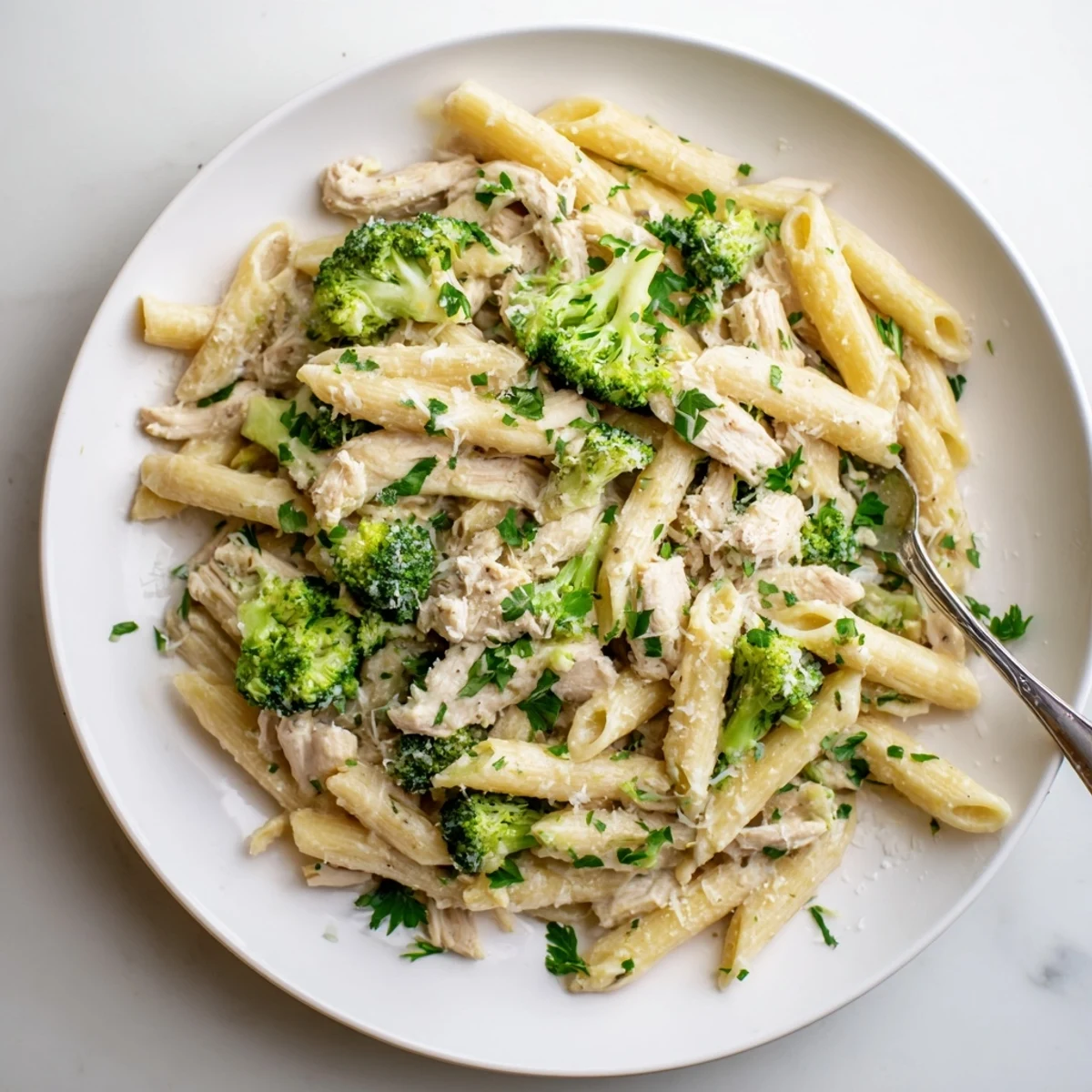 Creamy rotisserie chicken broccoli pasta in white sauce topped with fresh parsley