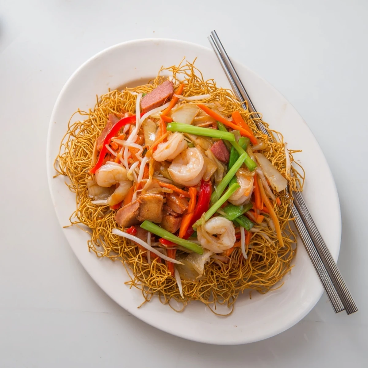 Golden crispy Cantonese chow mein topped with savory stir-fried vegetables and tender meats in glossy sauce