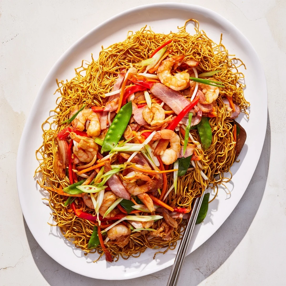 Homemade Cantonese chow mein served on white platter with bean sprouts, peppers, shrimp, chicken and char siu