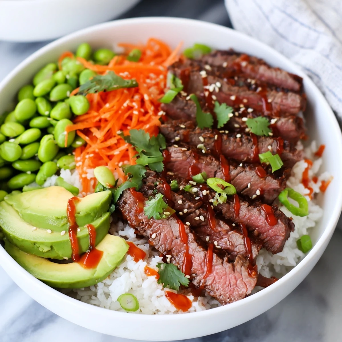 Protein-packed flank steak bowl displaying tender sliced beef, crisp cucumber, carrots, and zesty sauce in a colorful arrangement