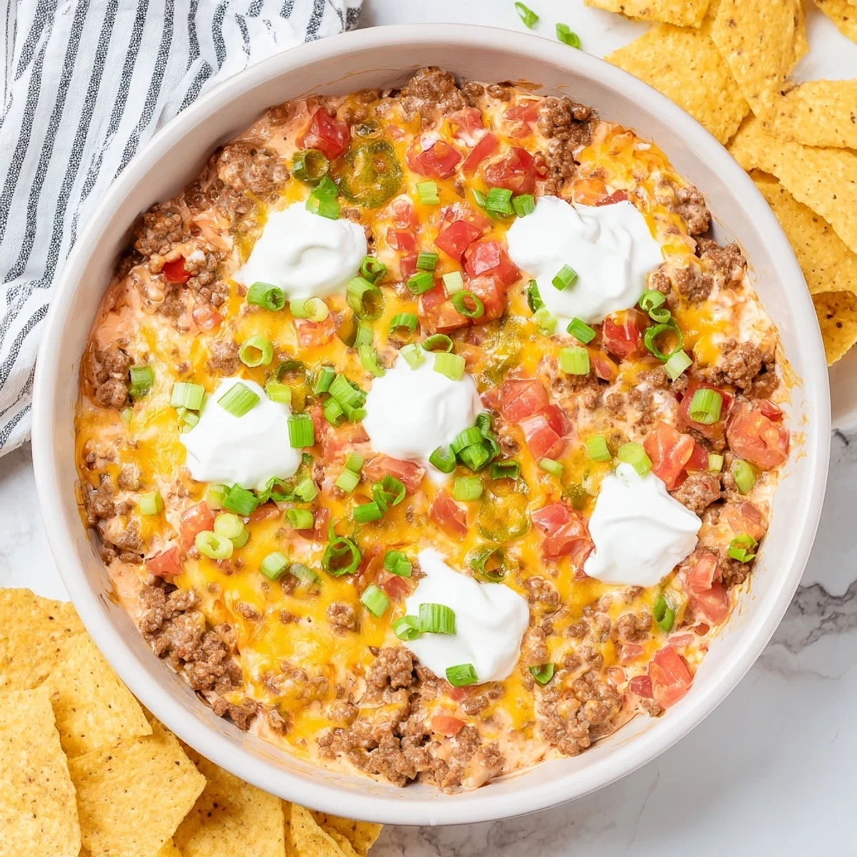 Golden melty Rotel dip with seasoned ground beef drizzled over rich sour cream