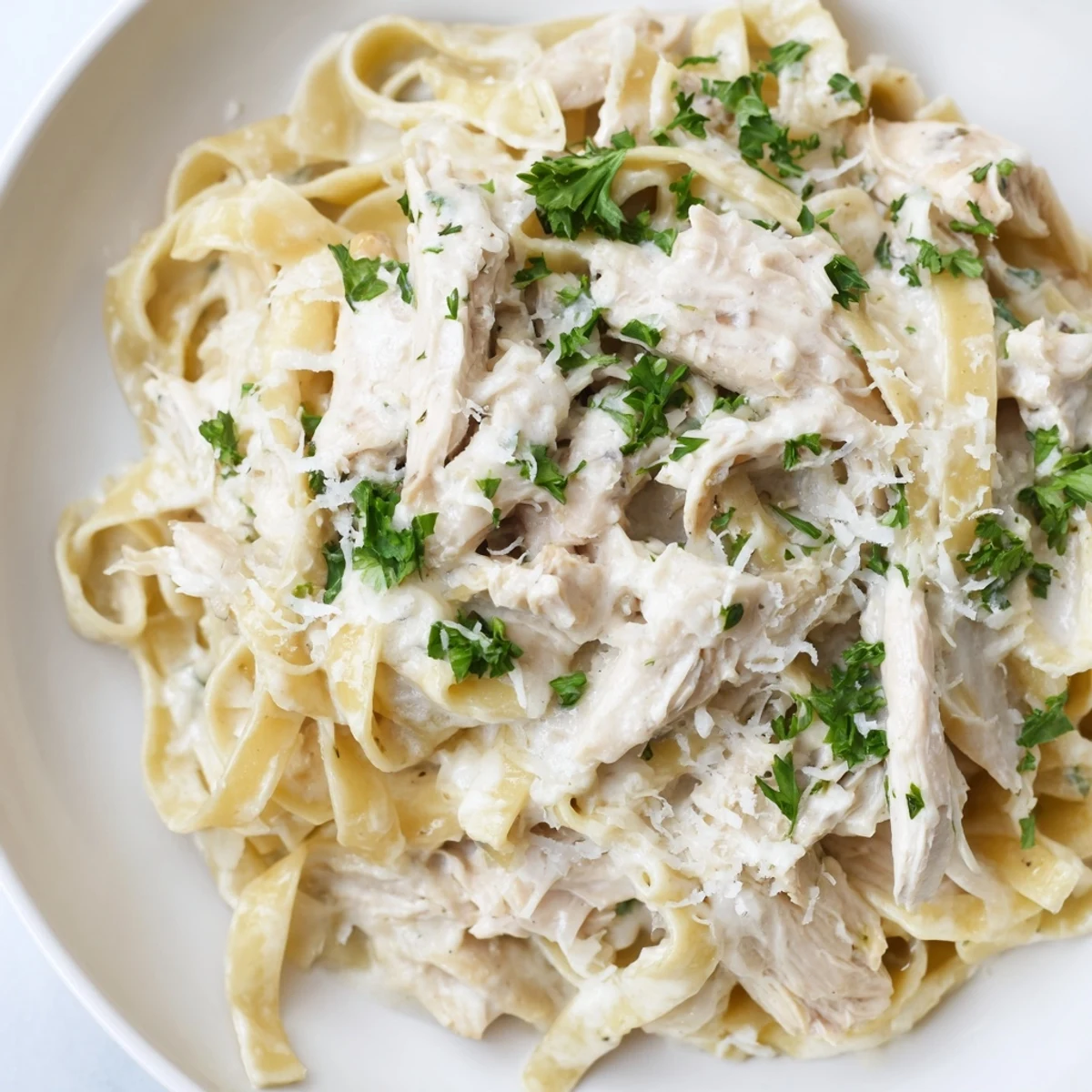 Slow cooker chicken Alfredo pasta featuring rich white sauce and shredded chicken breasts served over al dente noodles