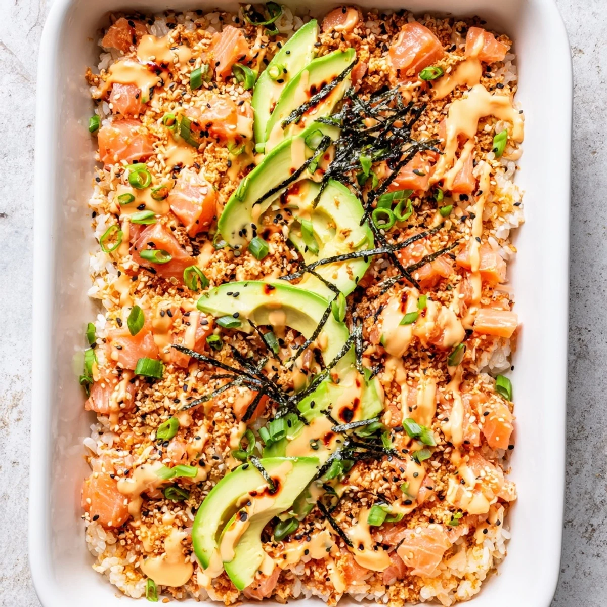 Golden salmon sushi bake topped with creamy spicy mayo and fresh avocado slices