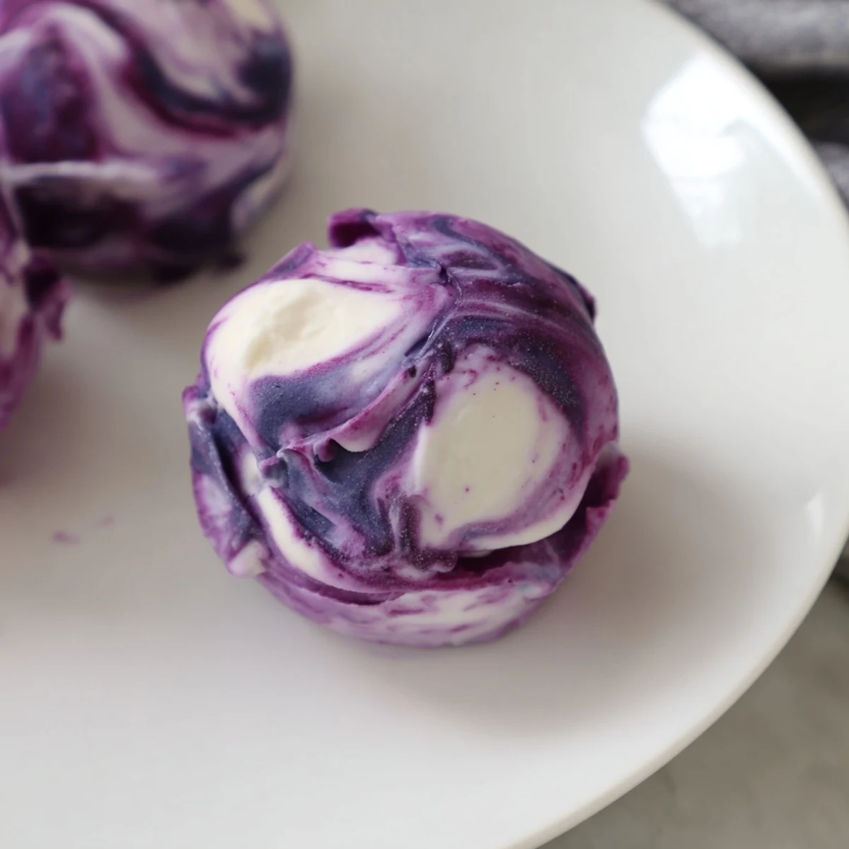 Frozen blueberry swirl yogurt bites arranged in rows showing purple berry streaks against white