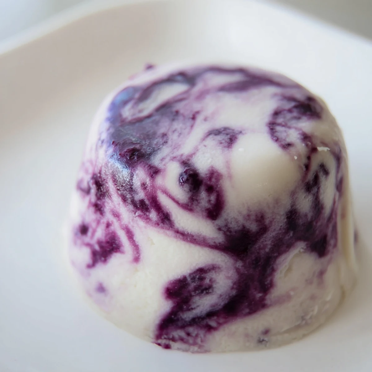 Creamy Greek yogurt bites swirled with homemade blueberry compote on a white baking sheet