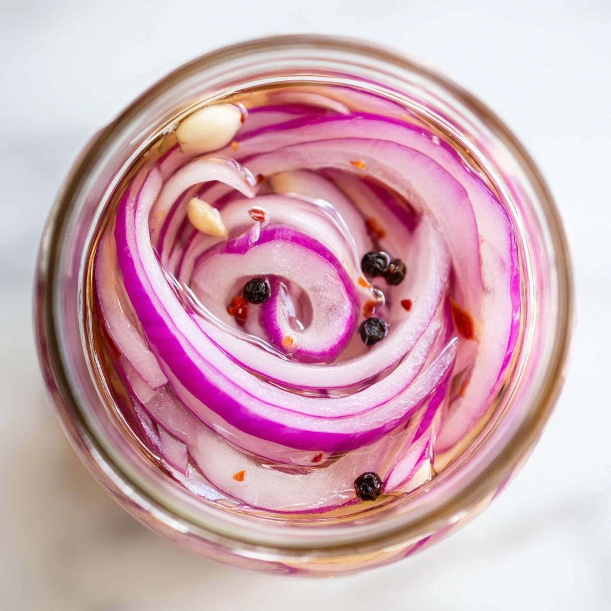 Close-up of tangy hot honey pickled red onions arranged neatly on a white serving plate