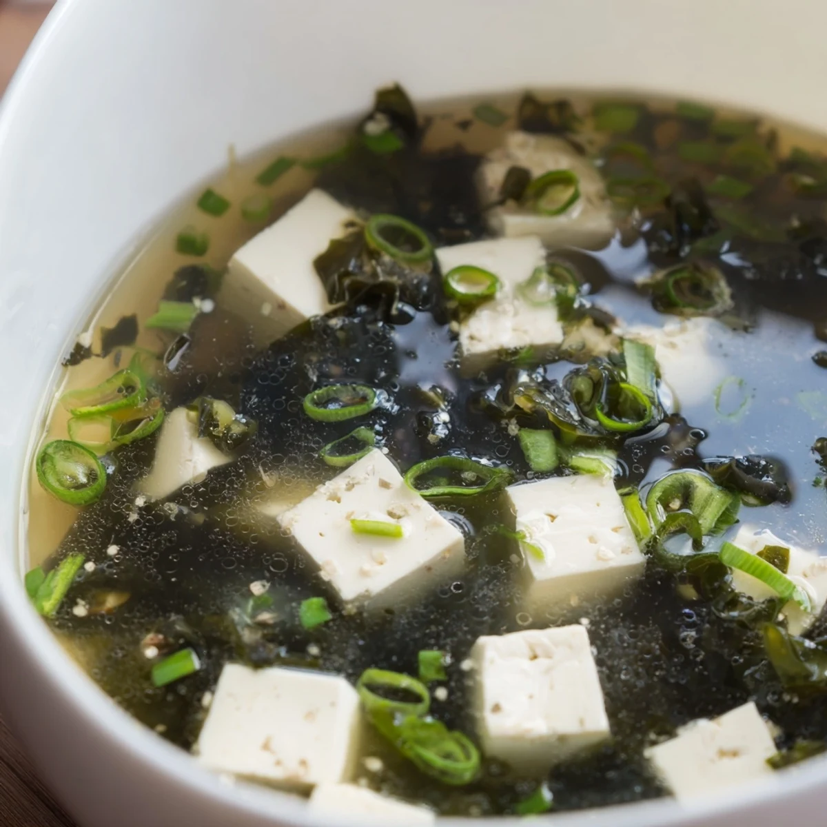 Steaming bowl of authentic Japanese miso soup with soft tofu cubes and vibrant green onion garnish