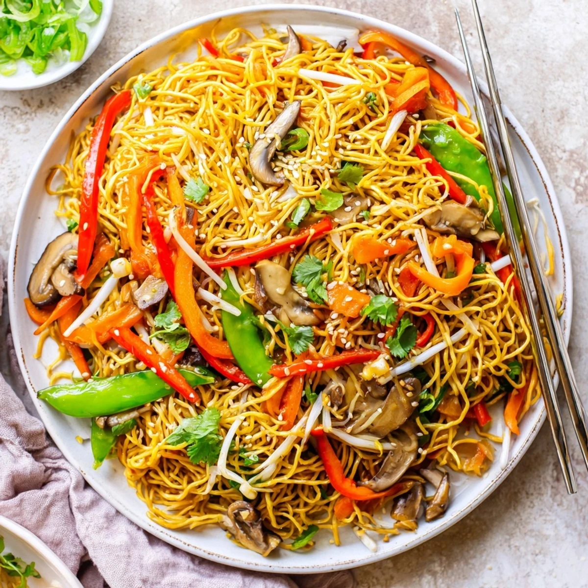 Platter of crispy noodle chow mein featuring bell peppers, carrots, and snow peas in glossy sauce