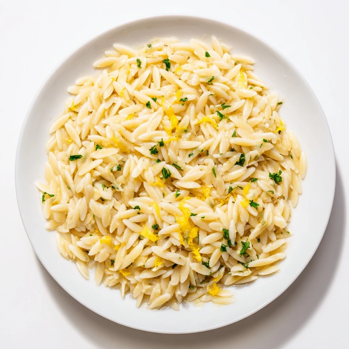 Creamy lemon orzo with bright green parsley garnish on a rustic wooden table