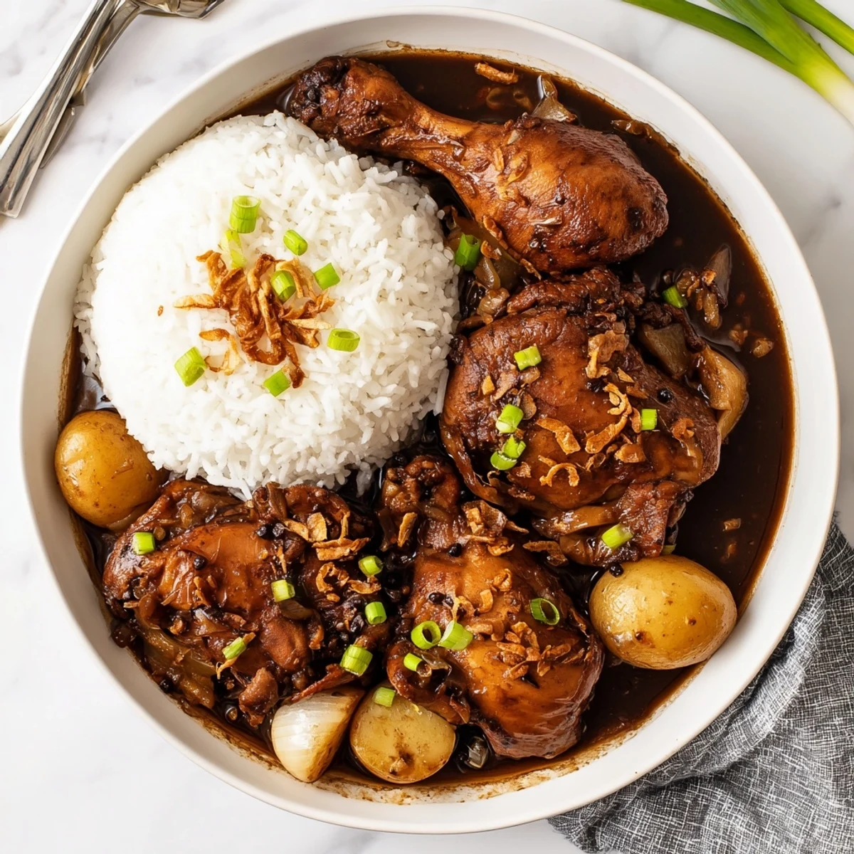 Golden brown Filipino chicken adobo braised in savory soy vinegar sauce with garlic