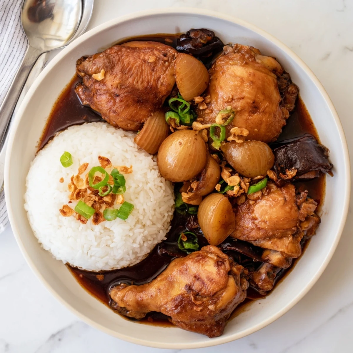 Tender chicken adobo simmered in rich dark glaze served over fluffy white rice