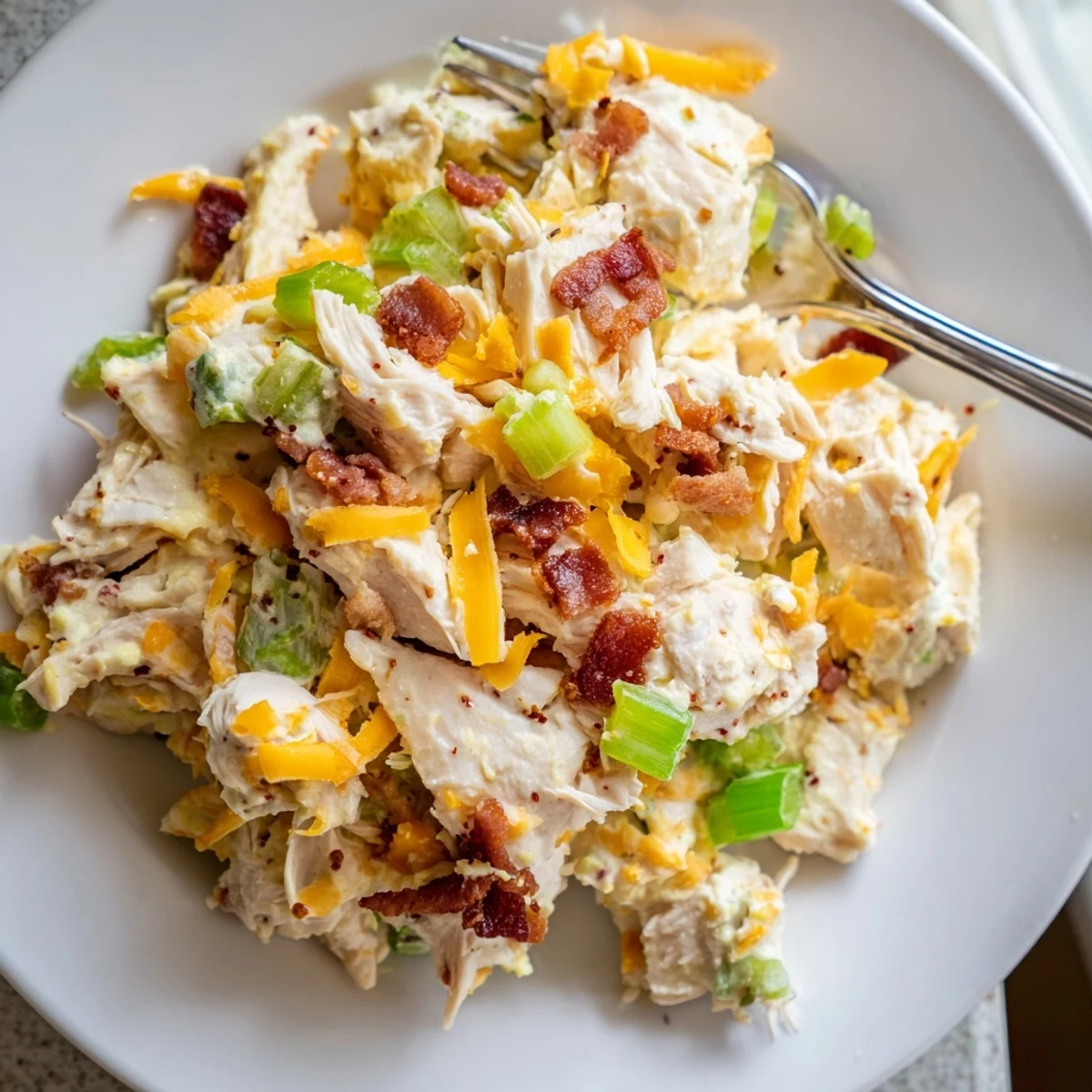 Creamy keto chicken salad loaded with crispy bacon, jalapenos, and melted cheddar cheese in a white bowl
