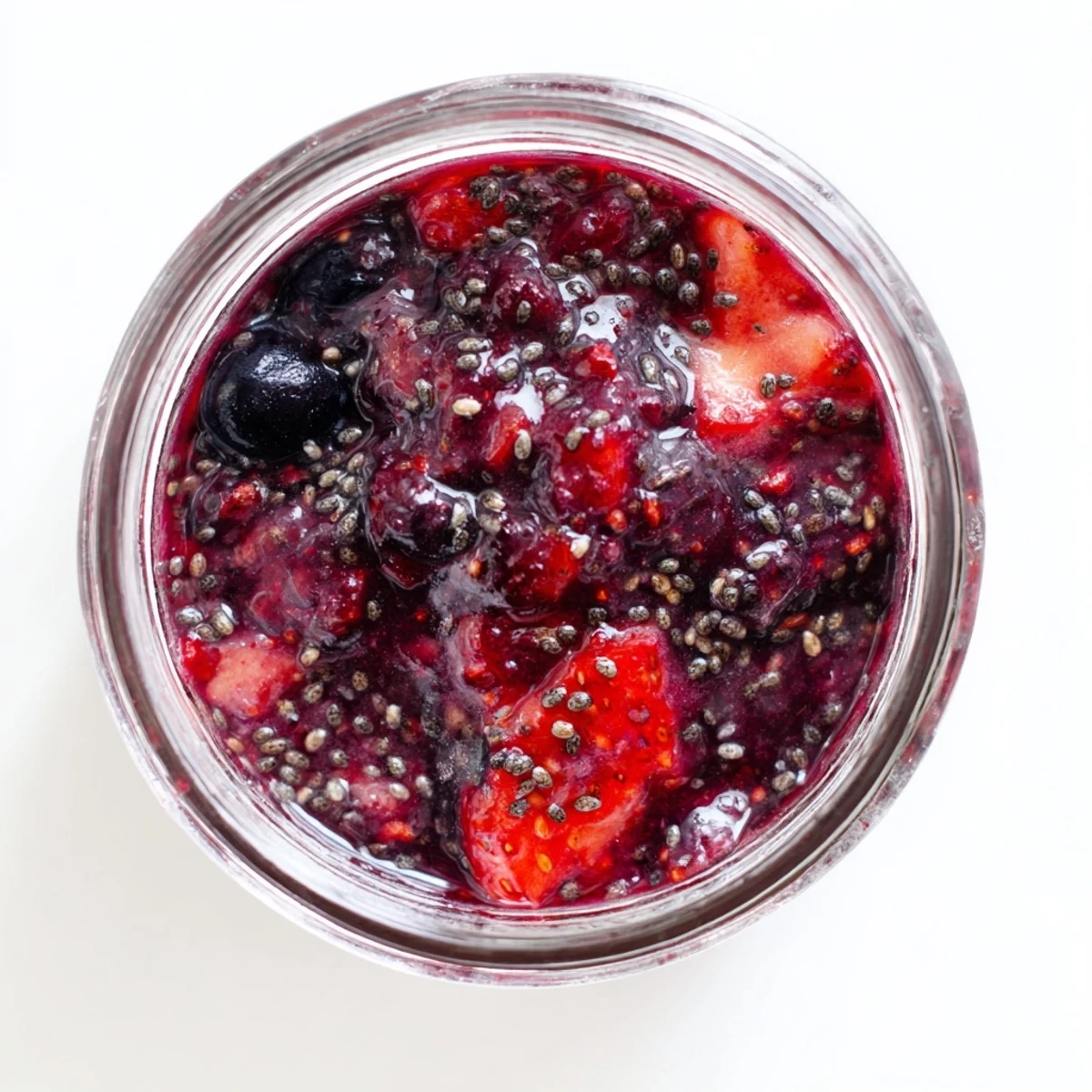 Glass jar filled with thick easy berry chia seed jam topped with plump whole chia seeds