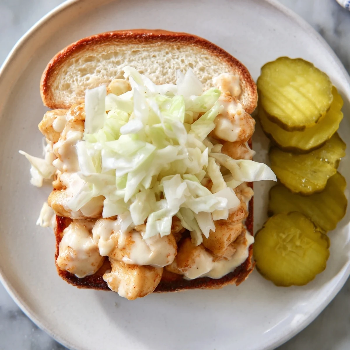 Southern-style Alabama BBQ chicken chopped sandwich featuring juicy sauced meat and fresh cabbage slaw on golden toasted bread