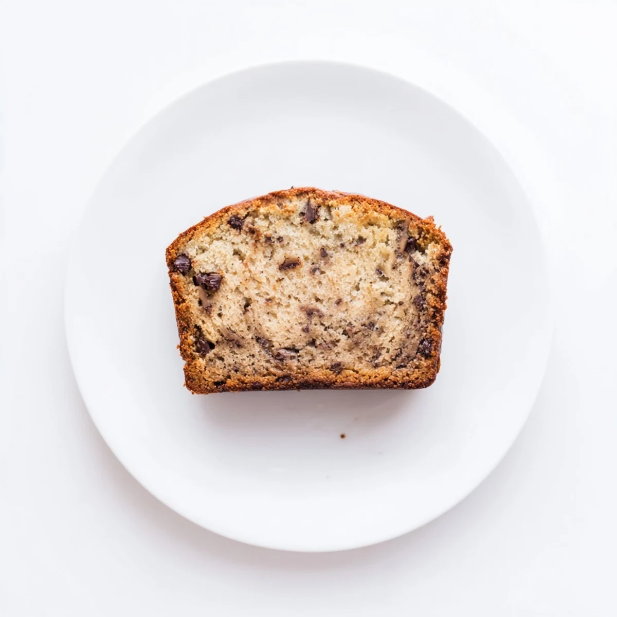 Moist banana bread slice studded with semi-sweet chocolate chips on a white plate