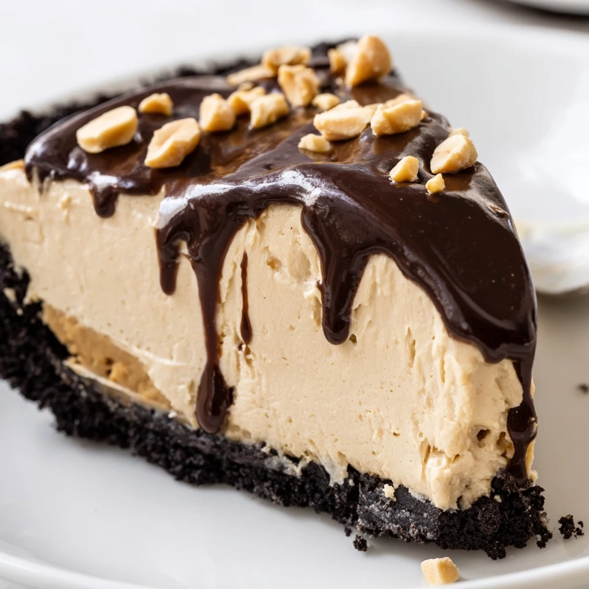 Creamy no bake peanut butter pie sliced and topped with glossy chocolate ganache drizzle