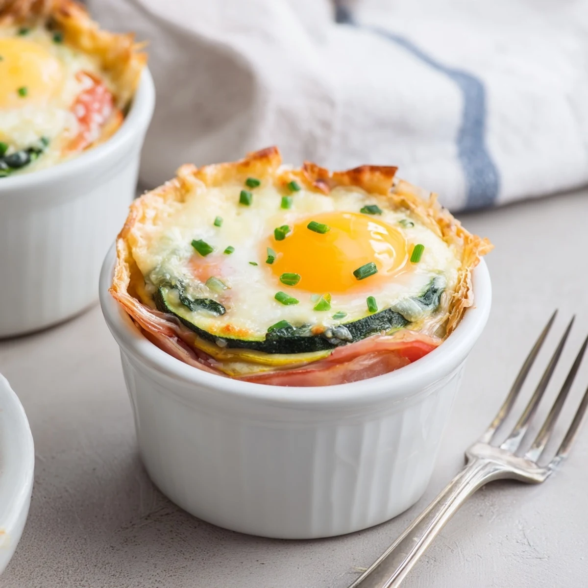 Golden baked eggs Napoleon with runny yolks nestled in creamy cheese sauce and layered vegetables