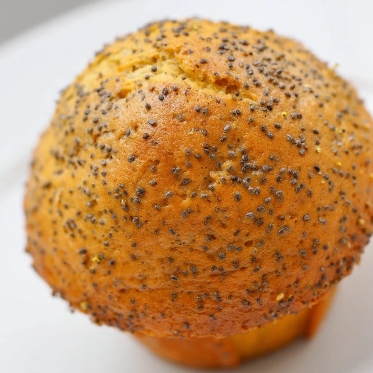 Golden lemon poppy seed muffins with domed tops sit in a rustic muffin tin ready to serve