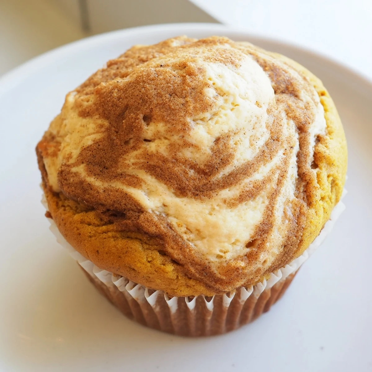 Warm chai pumpkin cheesecake muffins with swirled spiced cream cheese filling on rustic parchment paper.