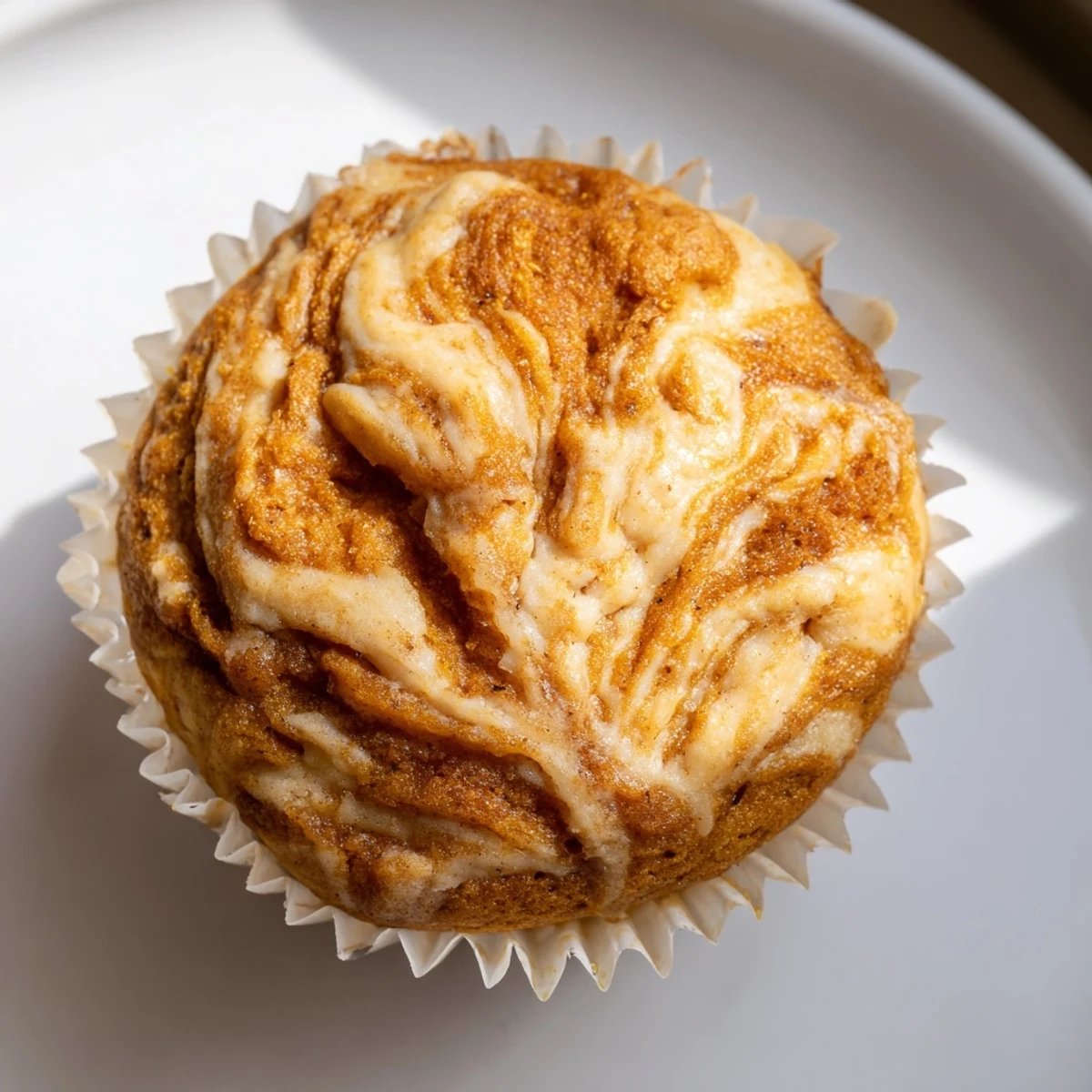 Golden pumpkin muffins topped with creamy chai-spiced cheesecake swirls dusted with cinnamon sugar.