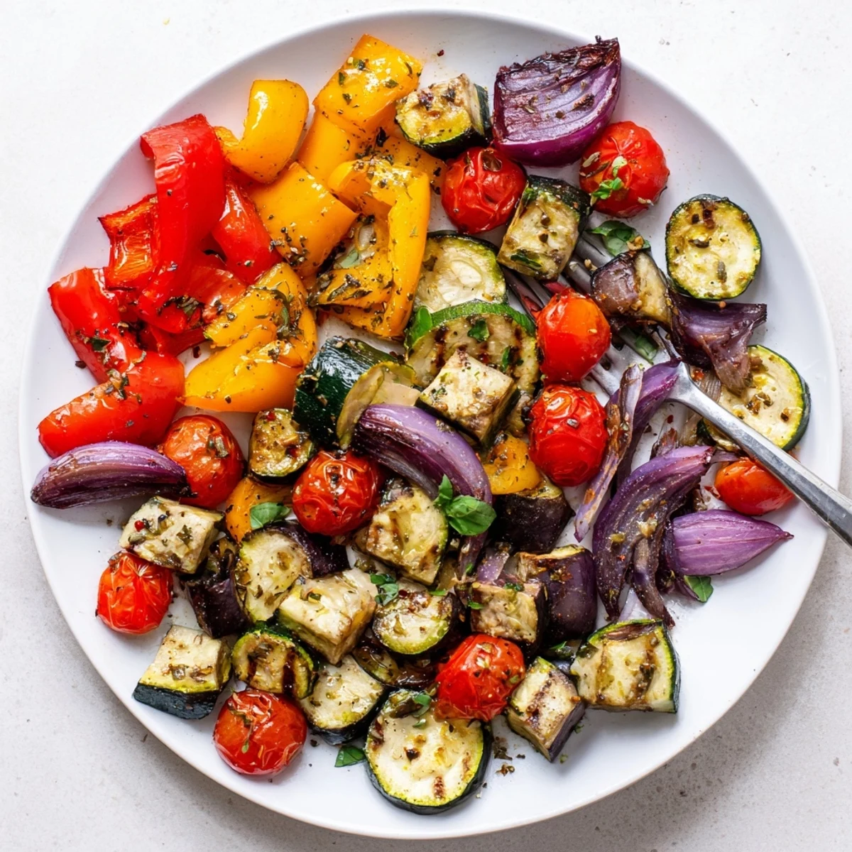 A colorful side dish of classic Mediterranean roasted vegetables garnished with fragrant basil leaves
