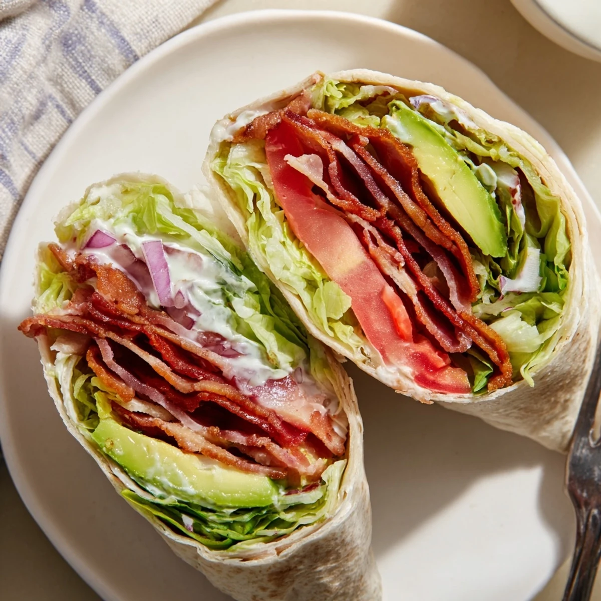 Meal Prep BLT Wraps stacked on cutting board, crispy bacon and bright tomatoes