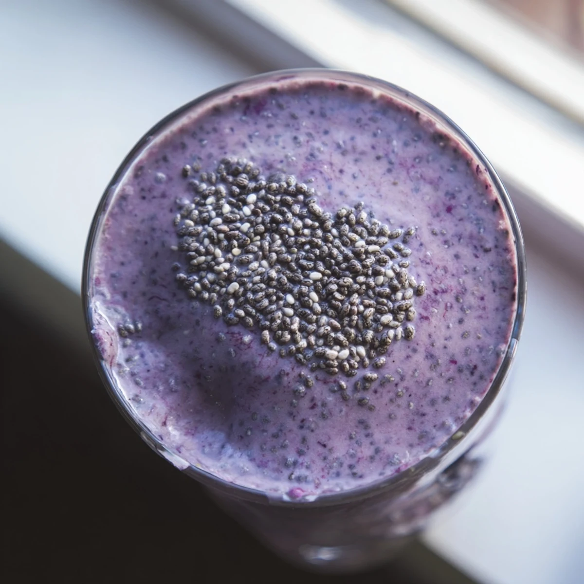 Thick purple chia seed smoothie topped with fresh berries in a clear glass