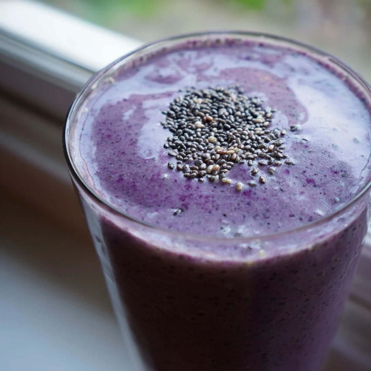 Vibrant purple chia seed smoothie with visible chia seeds garnished with sliced strawberries