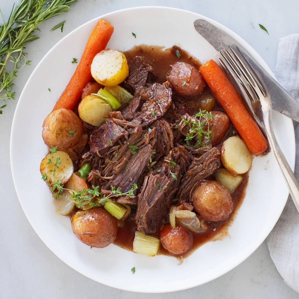 Tender herb braised beef chuck roast with carrots and celery in rich red wine sauce