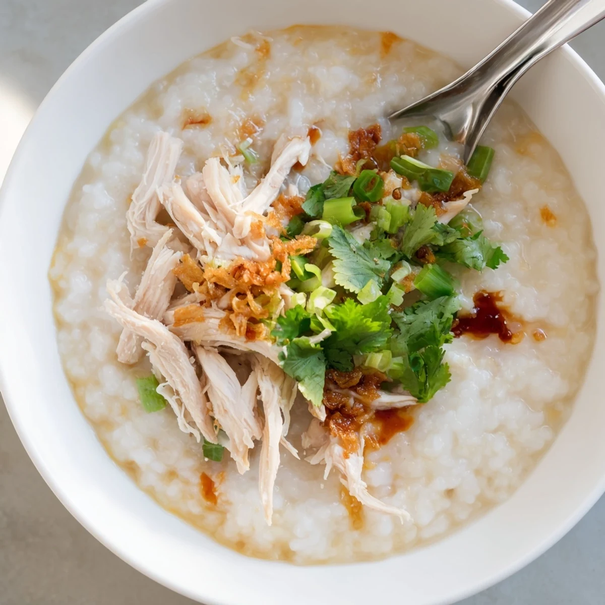 Steaming bowl of Chinese chicken congee garnished with cilantro and fried shallots