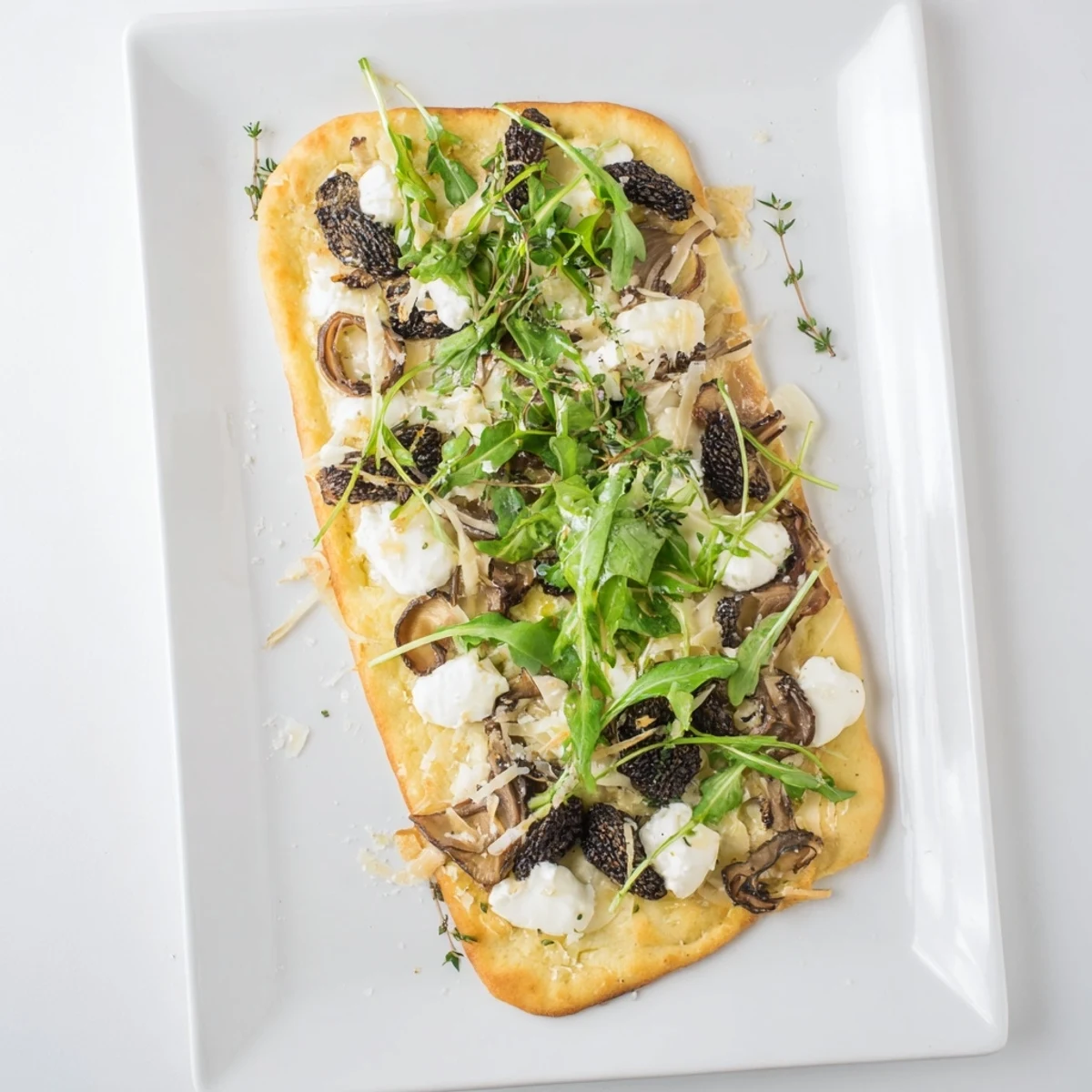 Golden Morel Mushroom Arugula Flatbread with truffle oil drizzle featuring melted mozzarella and goat cheese