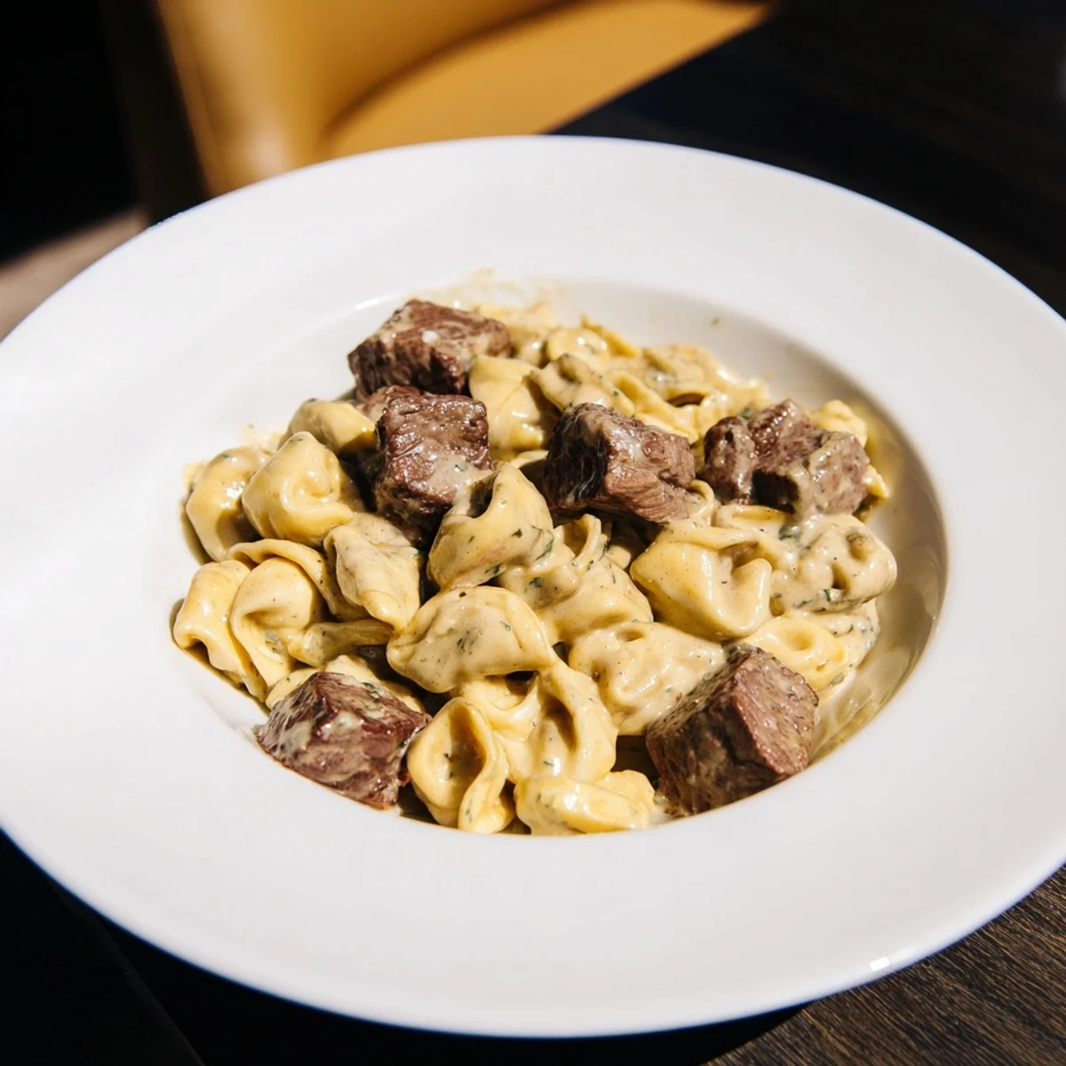 Close-up of garlic steak tortellini pasta dish coated in a buttery parmesan sauce
