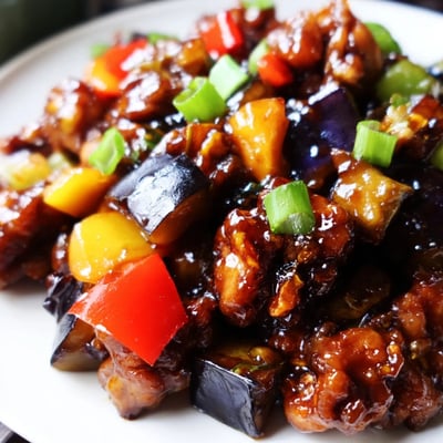 A serving of Black Vinegar Chicken With Bell Peppers And Eggplant paired with fluffy white steamed rice. 