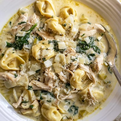 Hearty slow cooker chicken tortellini plated with vibrant carrots, celery, and a heavy cream sauce